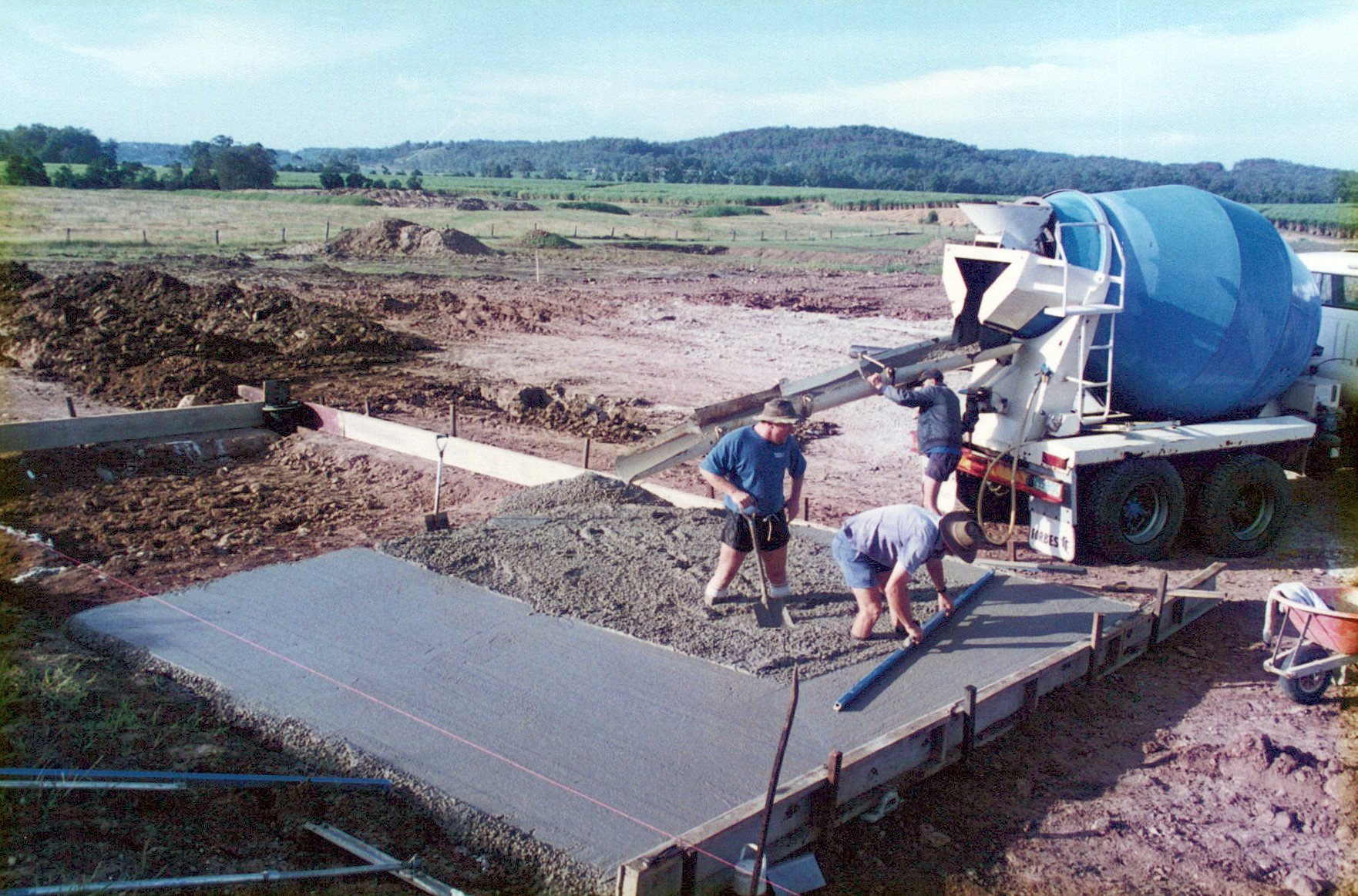 concrete mixer in action at a construction site, with workers and equipment nearby, emphasizing the building process.