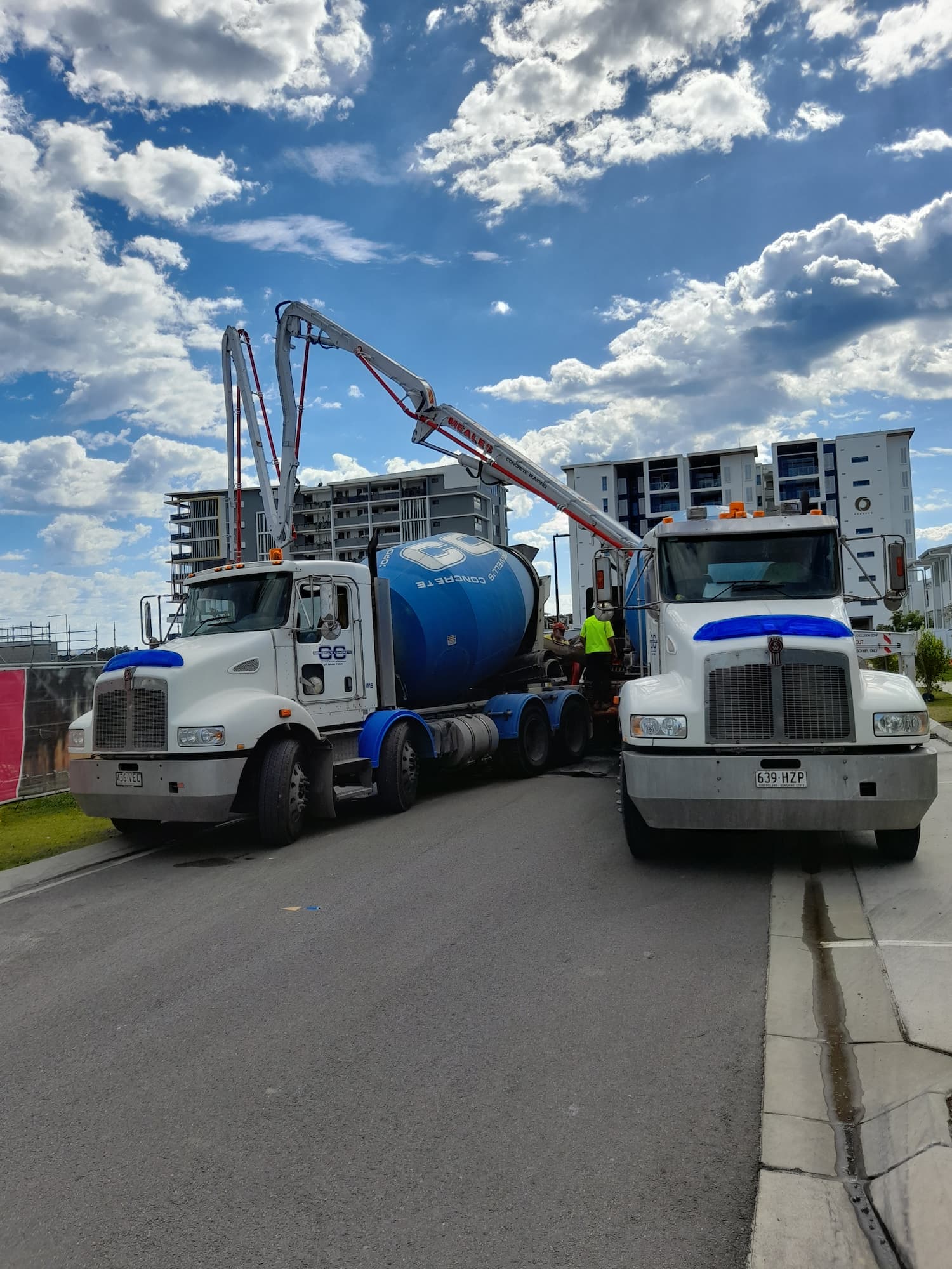 A blue and white truck parked on the roadside, with trees and a clear sky in the background.