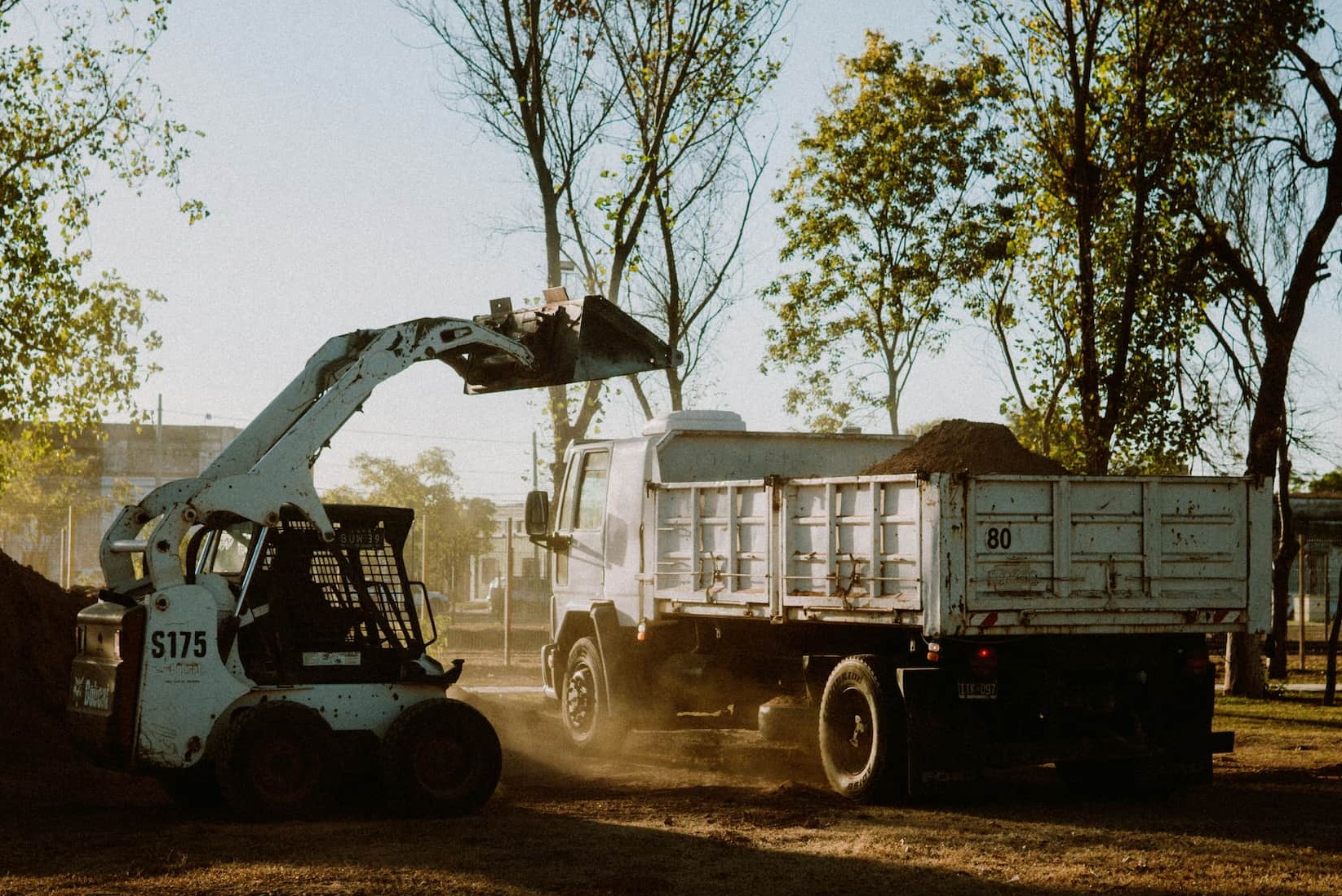 A dump truck parked beside another dump truck, actively loading materials for transport.